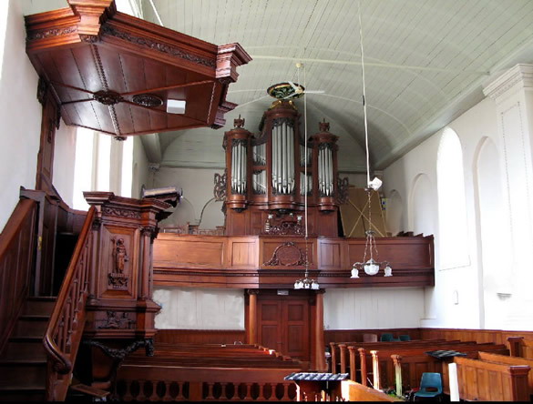 Interieur van de kerk met links de preekstoel met trap en klankbord, daarvoor het doophek en achter het orgel. Foto: ©Jur Kuipers.
